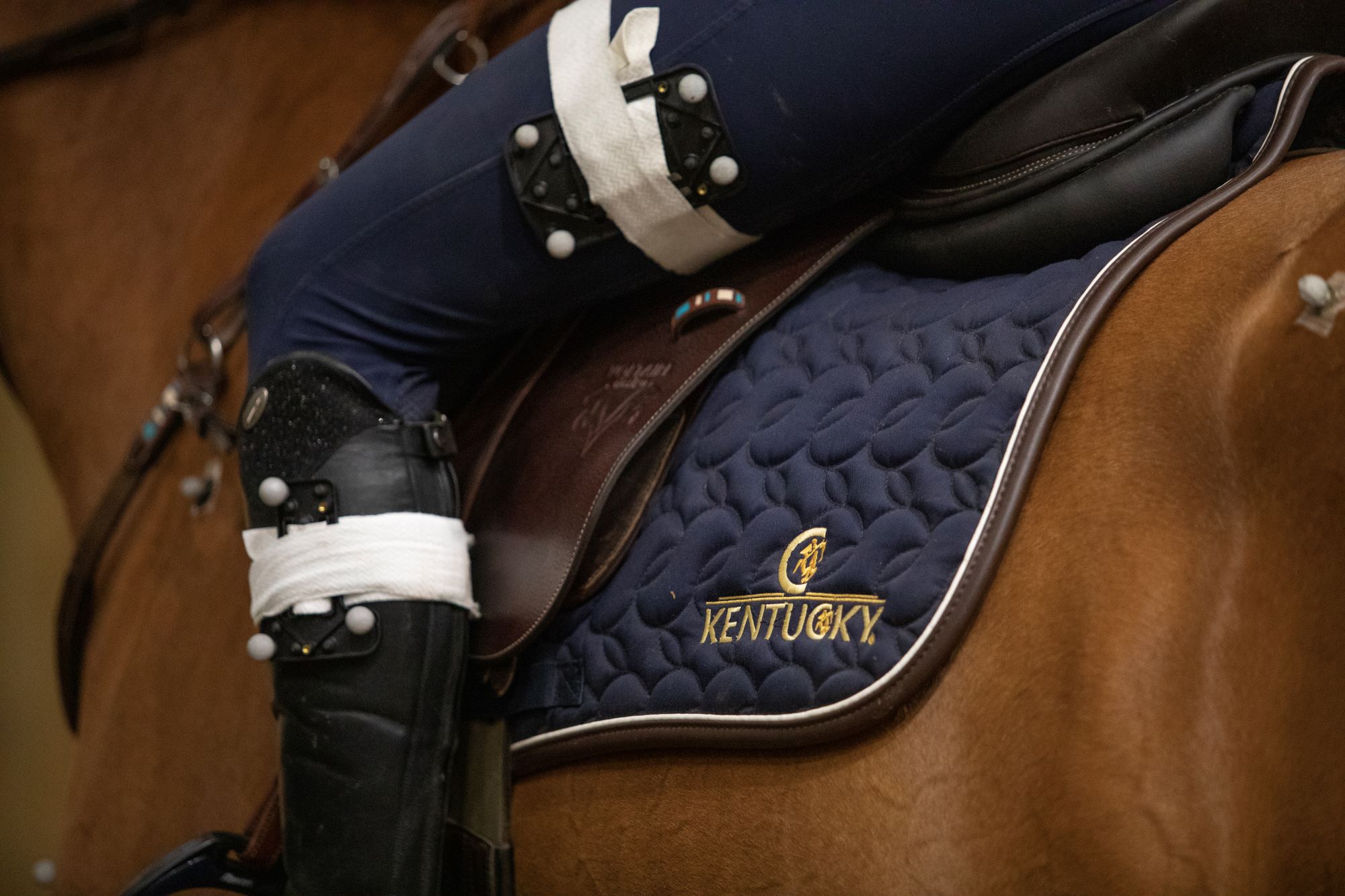 Motion-capture markers attached to a rider's leg beside a saddle